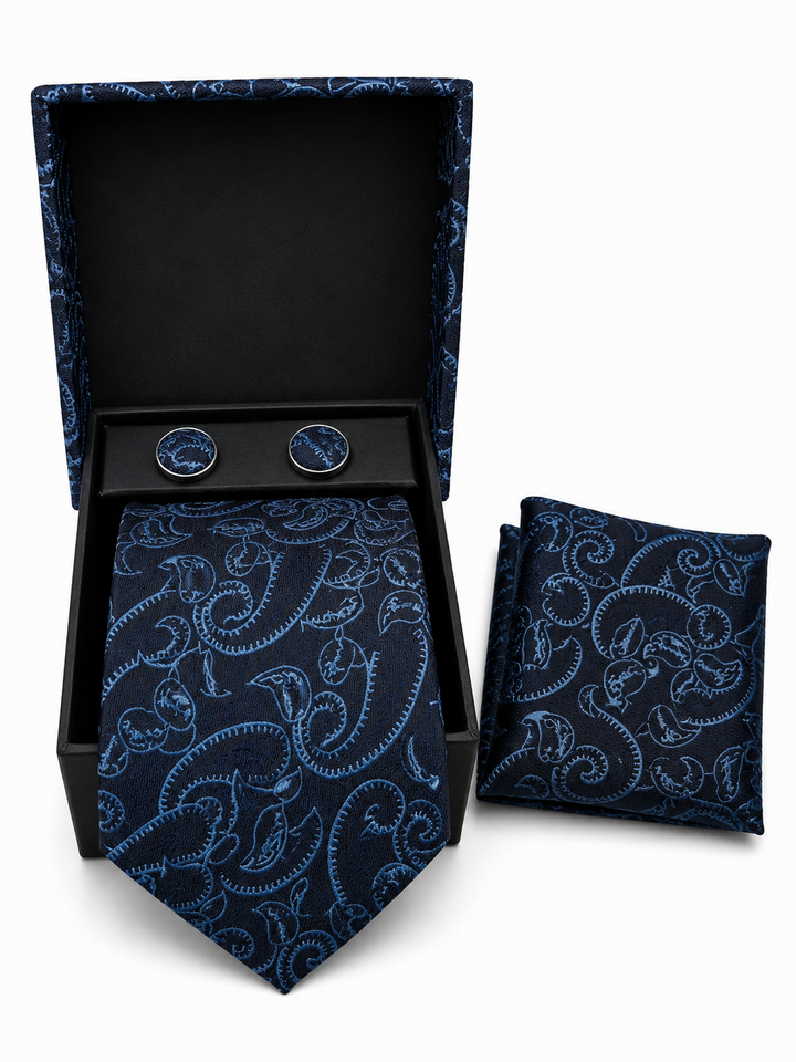 A men's necktie and matching pocket square set with round cufflinks, displayed in an open black presentation box on a white background. The fabric features a light blue paisley pattern on a dark navy base.