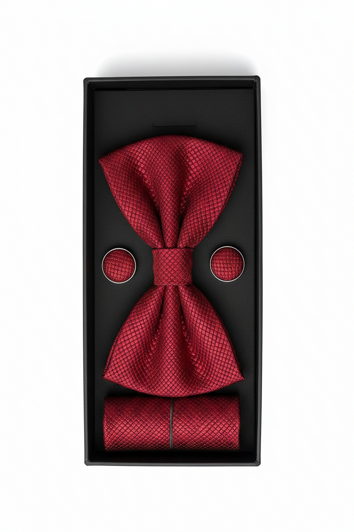 A red textured bow tie set with matching pocket square and round cufflinks, presented in a black gift box on a white background.