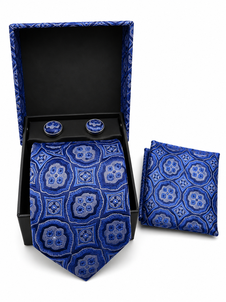 A men's necktie and matching pocket square set with round tie clips, displayed in an open black presentation box on a white background. The fabric features an intricate geometric medallion pattern in shades of royal blue, navy, and light blue.